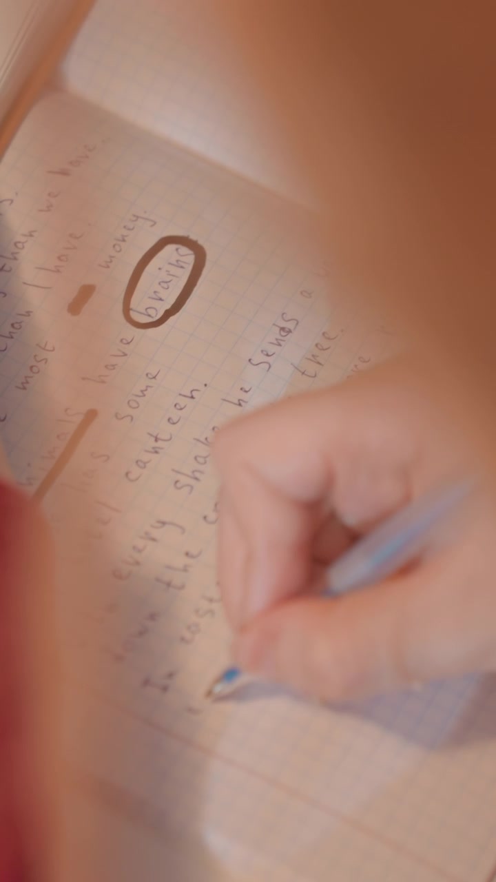Close up of person hand writing. Hand movements and text formation are. Notebook pages display cursive script underlined words like brains with consistent focus on close up view