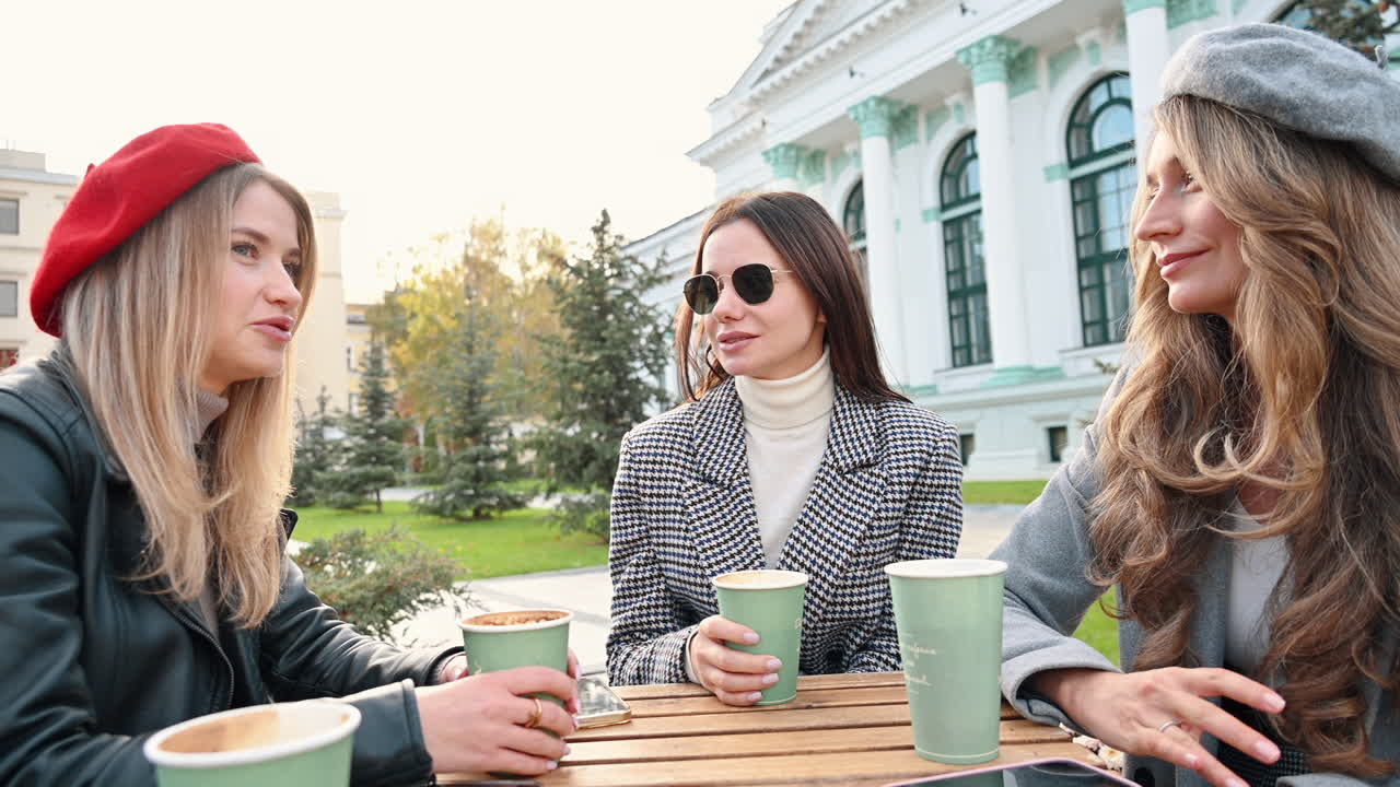 Three women talking and drinking coffee at a terrace