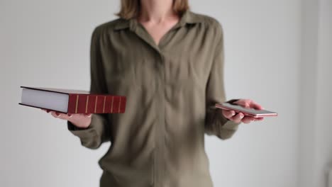 woman holding a book and a phone
