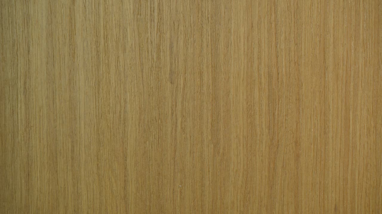 Watch as a sticky note with the message 'Picking up the kids' is carefully removed from a textured wooden door. This close-up shot highlights the grain and warmth of the wood under natural lighting