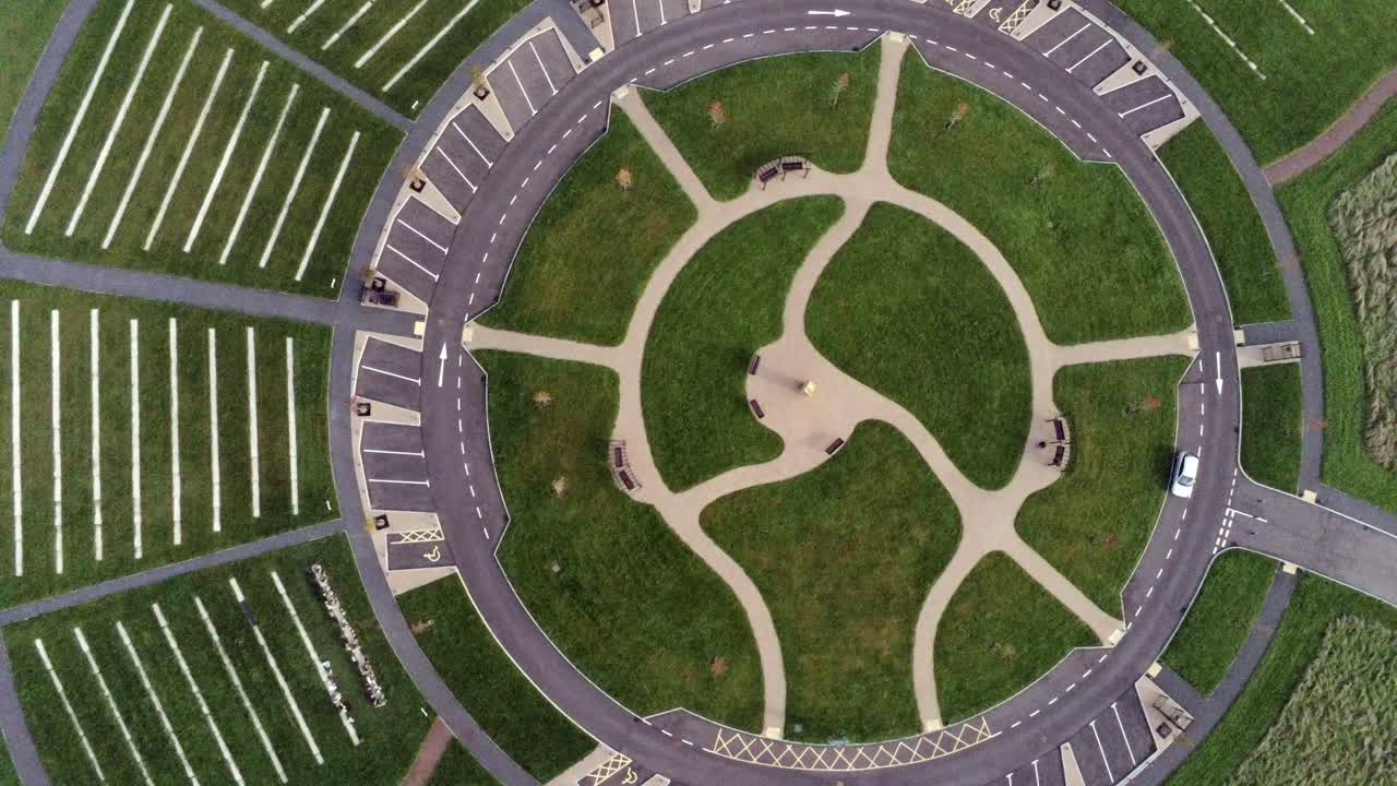 vista aérea de diseño circular sobre el jardín del cementerio paisajístico ornamental con estacionamiento alrededor del exterior rotación lenta a la izquierda