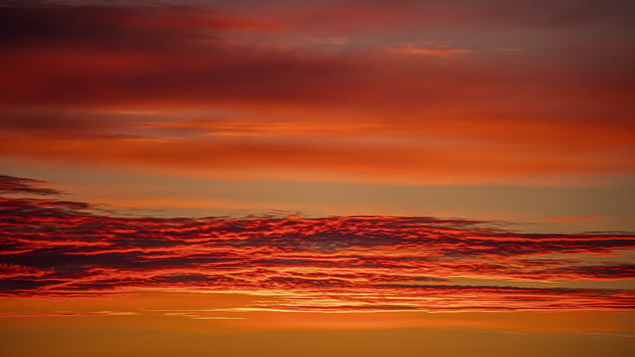 일몰 시간 동안 주황색 하늘에서 천천히 날아가는 권층운의 저속 촬영