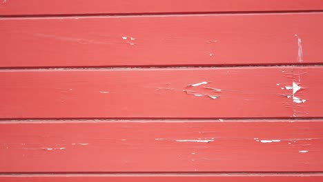 red painted wooden wall with peeling paint