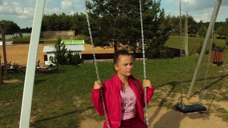 girl with red jacket swinging on the swing set