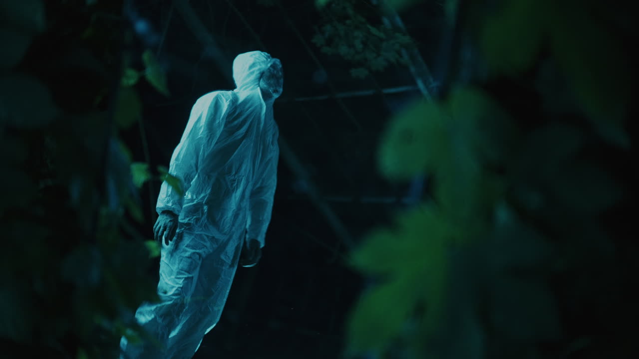 Person in a protective suit in a dark forest at night