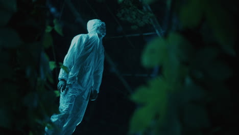 person in a protective suit in a dark forest at night