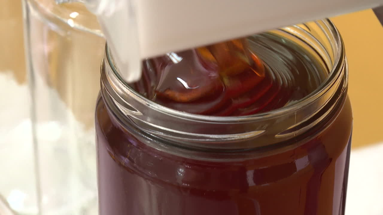 Honey pouring into glass jars