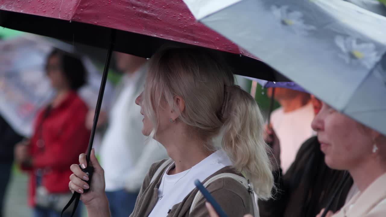 비가 오는 동안 우산을 들고 있는 여자 들