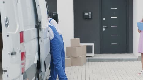 two young workers of removal company are loading boxes and furniture into a minibus