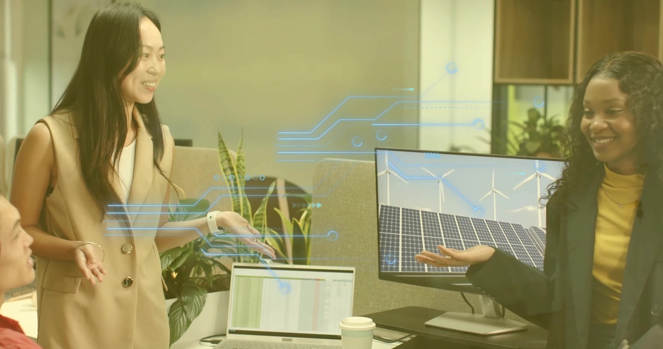 Donna in piedi che indica lo schermo del laptop e guida il piano per le energie rinnovabili mentre il collega mostra il monitor.