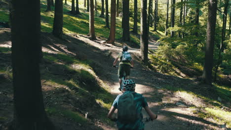 a group of three men riding mountain bikes fast down the trail - cinematic moving camera shot