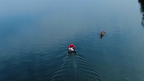 a red motorboat leading the canoe