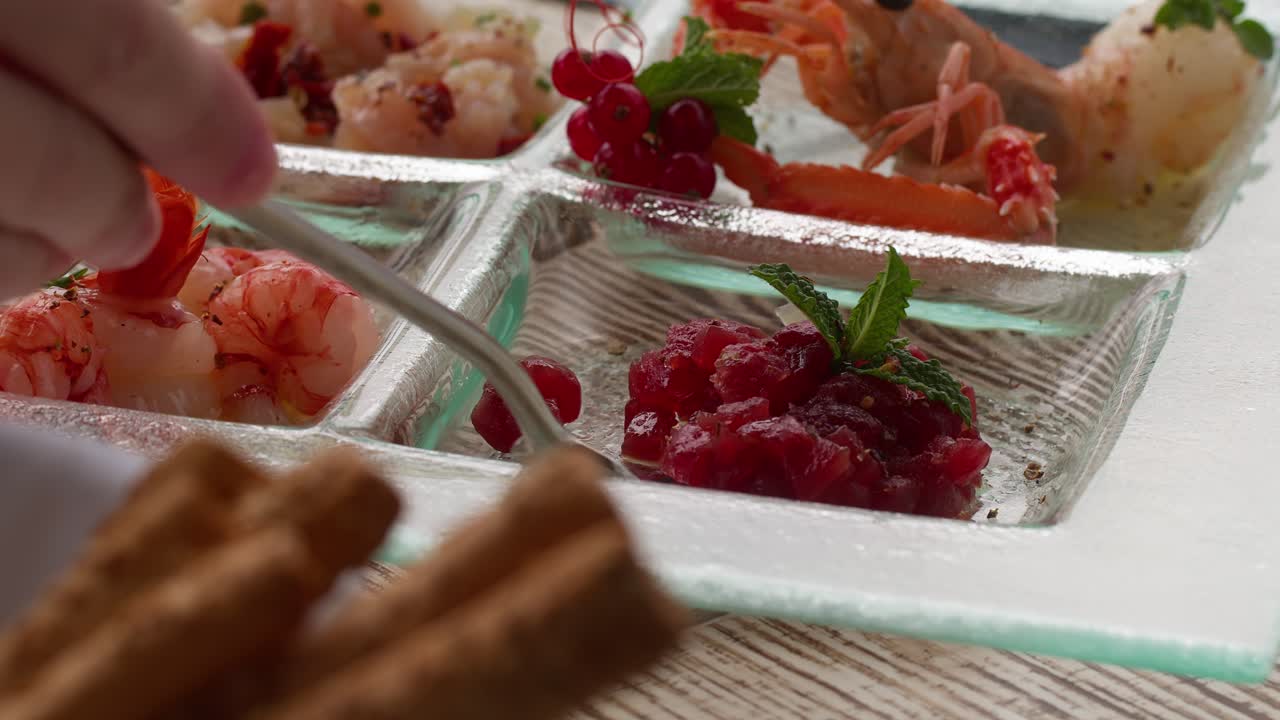 A fork picking up a Mediterranean snack from an aperitif plate, surrounded by seafood, in Taormina, Sicily, Italy (Taormina, Sicilia, Italia)