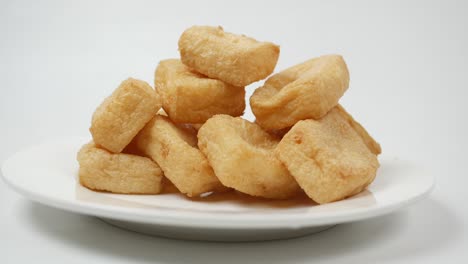 una pila de tofu frito en un plato sobre un fondo blanco .