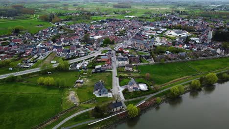Pullback-aerial-view-of-village-by-River-Schelde,-Belgium