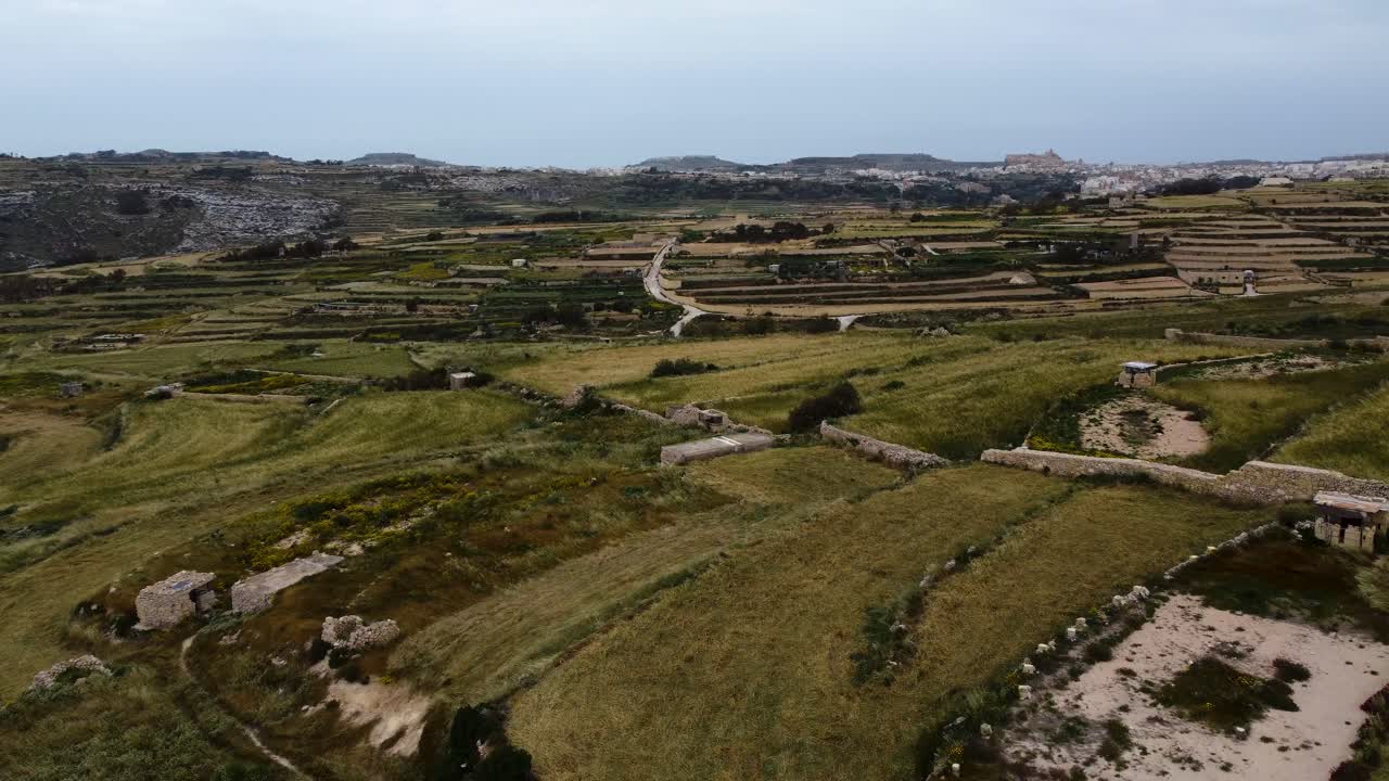 fotografía de un avión no tripulado de la campiña maltesa que muestra la ciudad en la distancia y las paredes rocosas de abajo