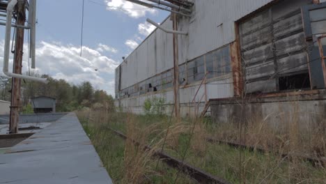 slider footage of overgrown railroad tracks at an abandoned, decaying factory