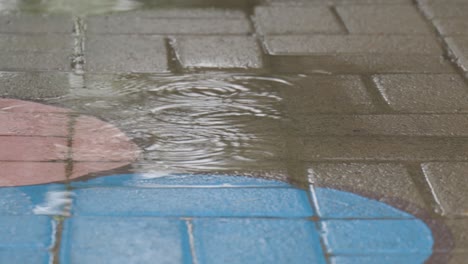 Cierre-La-Toma-Estática-De-Las-Gotas-De-Lluvia-En-El-Patio-De-Una-Escuela-Con-Un-Círculo-Pintado-De-Azul-En-El-Suelo