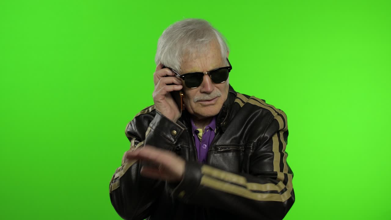 Avô caucasiano idoso e elegante, insatisfeito, falando ao celular.