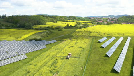 Tractor-spraying-pesticide-over-a-rapeseed-field-between-solar-panels