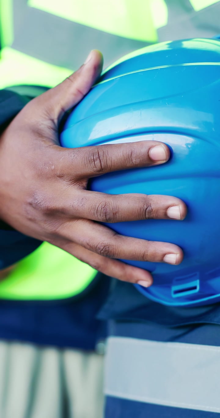 Operaio edile con casco di sicurezza blu in mano