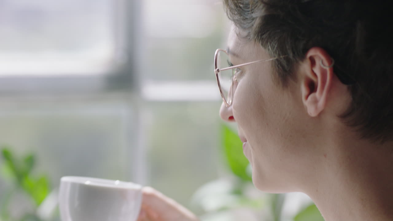 태블릿 컴퓨터를 사용하는 아름다운 백인 여성 집에서 커피를 마시고 편안한 아침을 즐기고 소셜 미디어 메시지를 검색하여 창밖을 바라보고 온라인 라이프 스타일을 가까이 공유합니다.