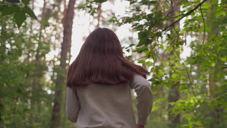 female athlete jogging across forest on sunny weather. young woman prepares for competitions performing physical exercises in nature on summer day