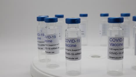 transparent empty glass vials with covid-19 vaccine label on rotating display