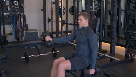 athletic man doing front dumbbell shoulder raises at gym in slow motion