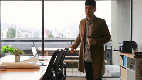 front view of young asian businessman walking with coffee cup in modern office 4k