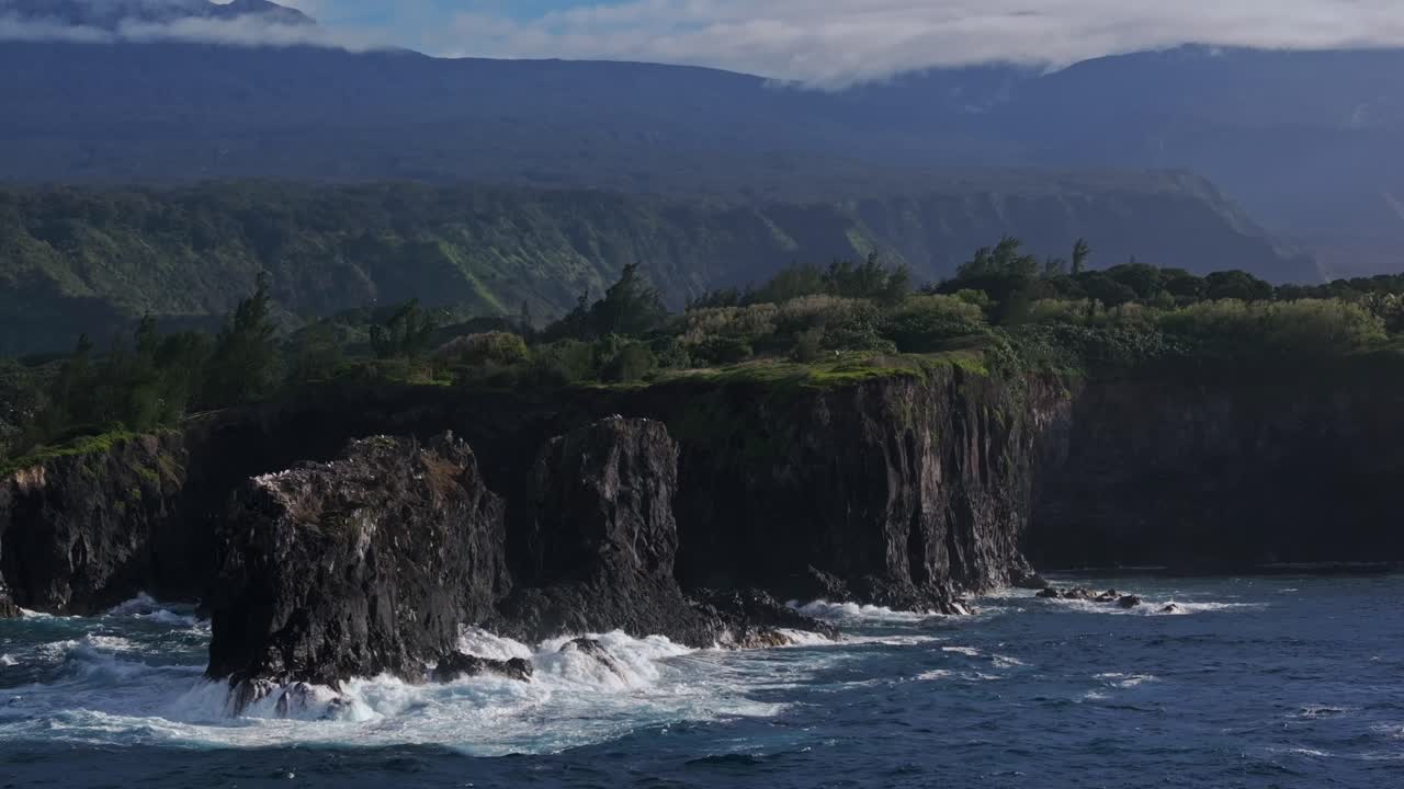 un amplio abanico aéreo de olas lavando sobre los acantilados por la costa norte de maui, hawai