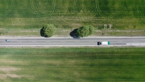 steady drone shot of a 2 lane highway with cars and trucks driving by