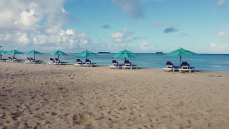 low angle drone orbit shot of beach chairs and umbrellas on a bright and clear morning