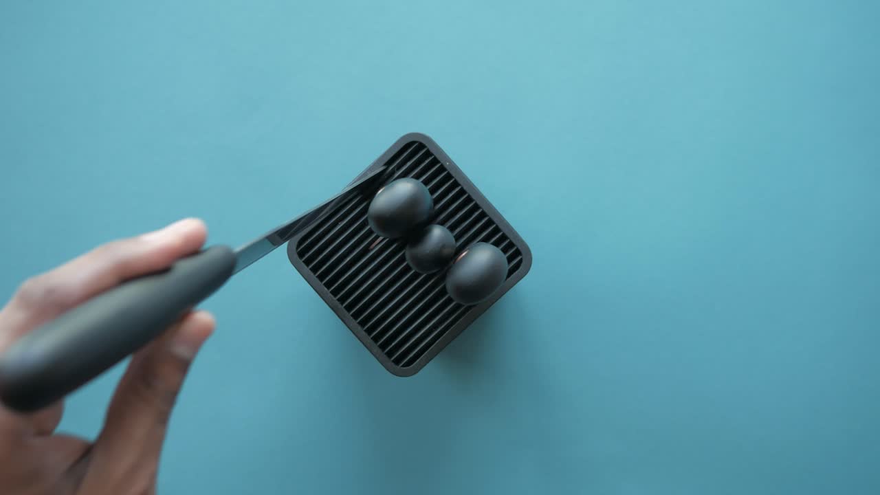 Hand holding small black device with decorative objects