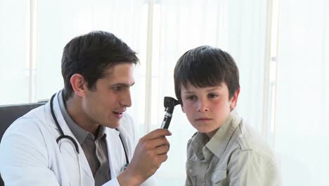 el médico examina las orejas de los niños en la oficina.