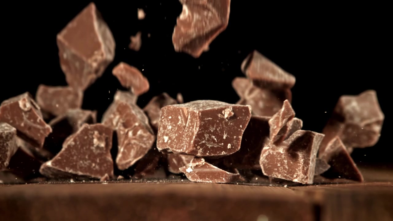 Movimento rallentato di pezzi di cioccolato che cadono su una superficie di legno