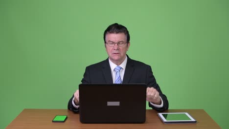 senior handsome businessman using laptop and getting bad news