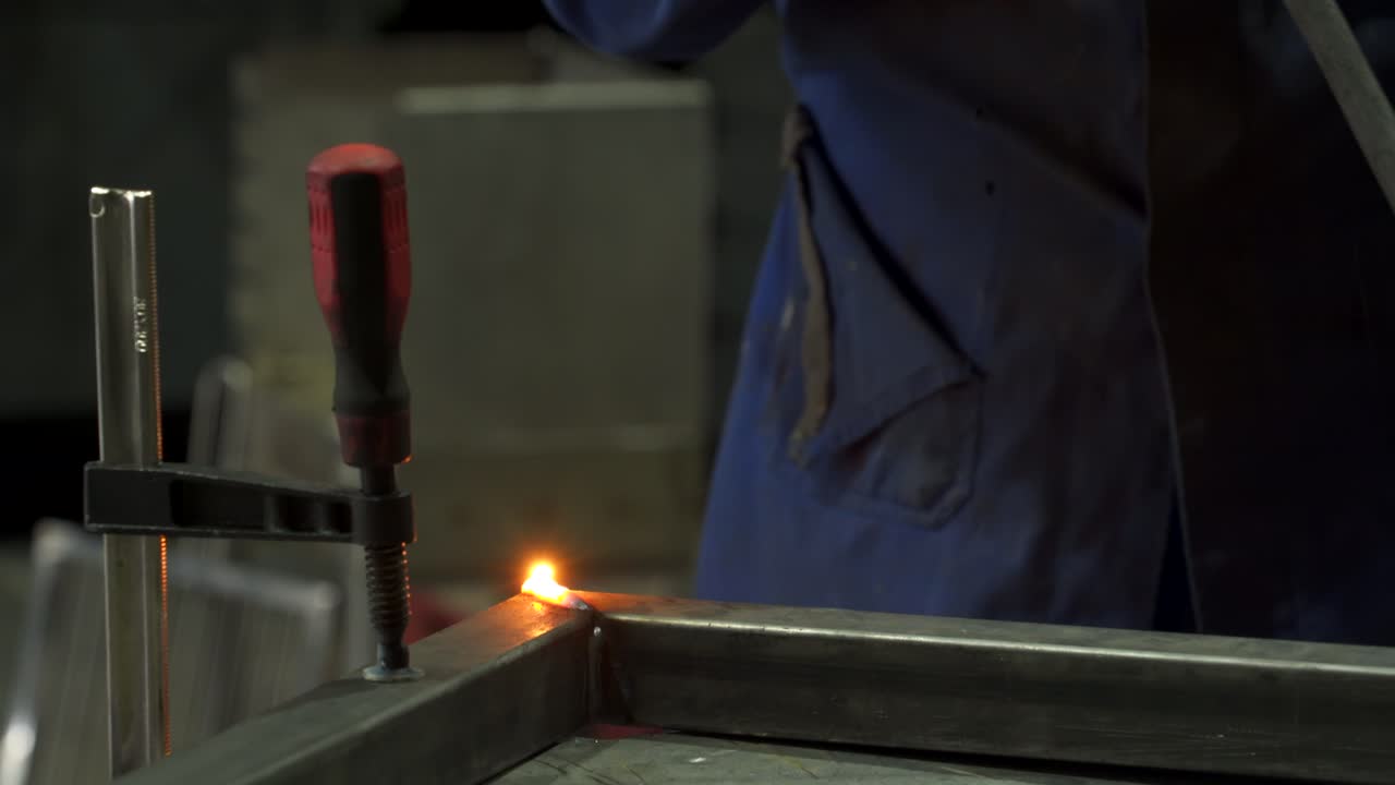 익명의 노동자가 작업장에서 금속 구조물을 용접하고 있습니다.