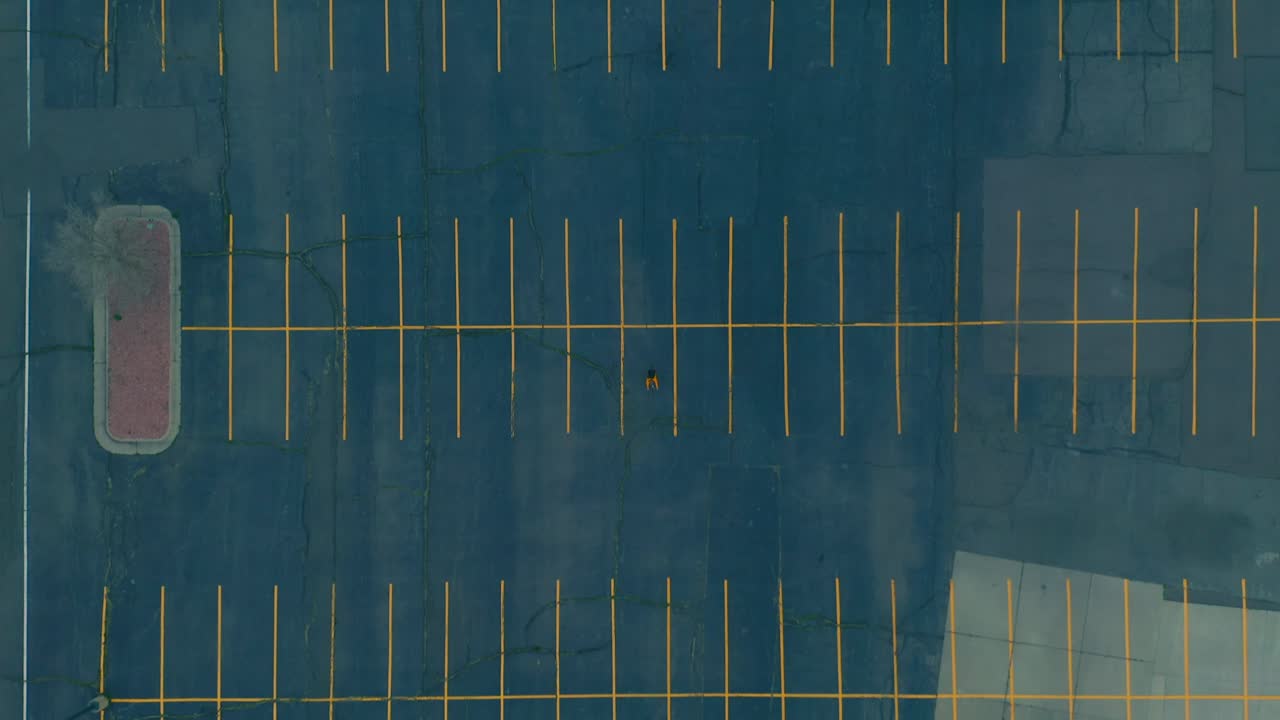 집에 머무르는 동안 비어 있는 넓은 주차장을 가로지르는 자전거 타는 사람의 하향식 공중 촬영