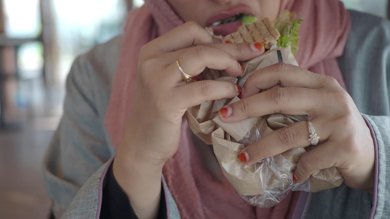 Una mujer comiendo un sándwich.