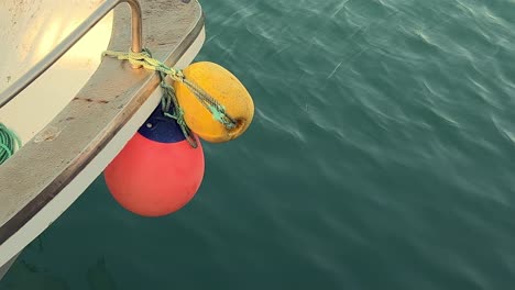 Buoys-line-the-sides-of-the-ship-vessel,-their-vibrant-hues-of-red-and-yellow-contrasting-against-the-backdrop-of-the-sea,-encapsulating-the-essence-of-maritime-life-in-all-its-colorful-splendor