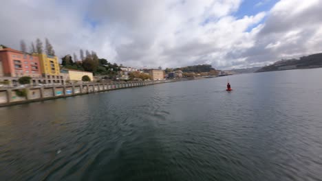 circle around a orange buoy in a blue water lake fpv drone orbit arrabida bridge