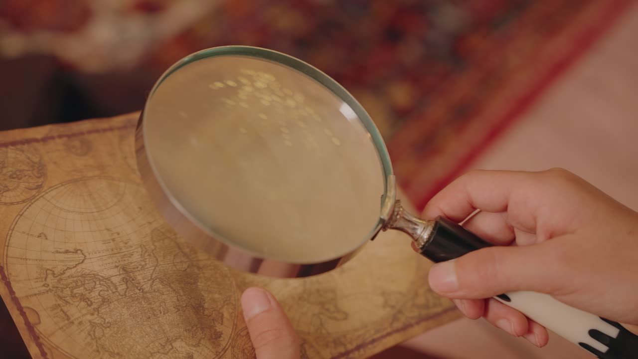 Close up of vintage map studied with magnifying glass in warm light