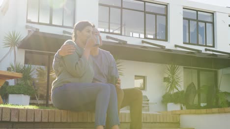 video of happy diverse couple talking and drinking coffee in garden