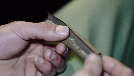 4.000 manos masculinas sosteniendo una articulación roma de neblina de hierba pura en papel de cigarro a cámara lenta listo para enrollar