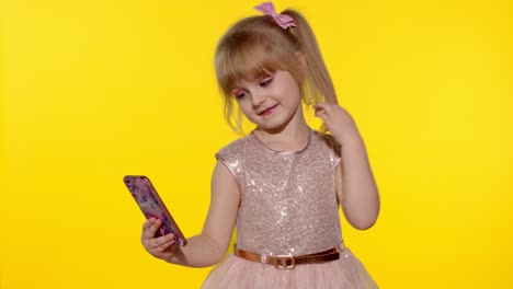 child girl using smartphone. portrait of blonde kid emotionally makes selfie on mobile phone