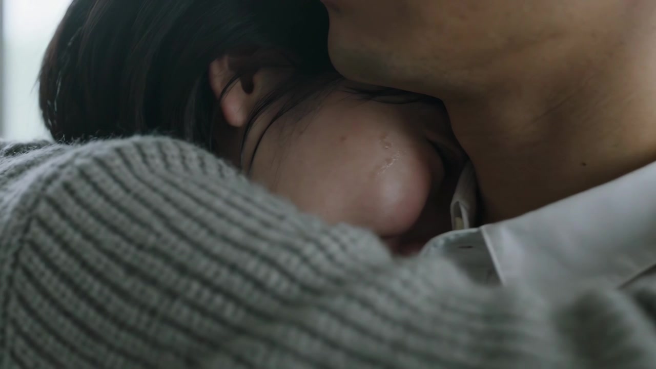 Seeking comfort, woman nuzzling man's neck near window, gray knit sweater and white collared shirt