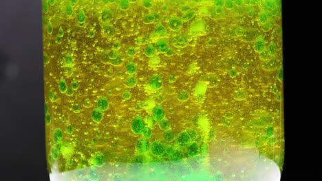 Watch the mesmerizing movement of green bubbles rising through a yellow liquid in this captivating visual experiment.
