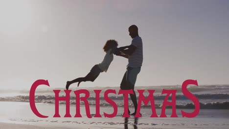 Animation-of-christmas-over-happy-african-american-father-having-fun-with-daughter-on-beach