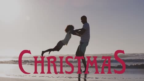 animation of christmas over happy african american father having fun with daughter on beach